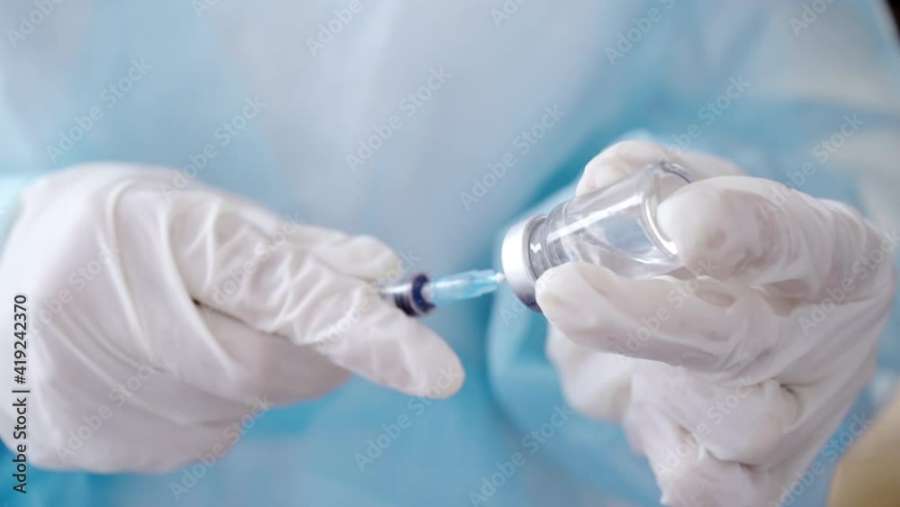 Syringe and Vaccine Vial in the Doctor's Hands. Close-up of Hands in Medical Gloves Filling a Syringe with Medication Syringe and Vaccine Vial in the Doctor's Hands. Close-up of Hands in Medical Gloves Filling a Syringe with Medication