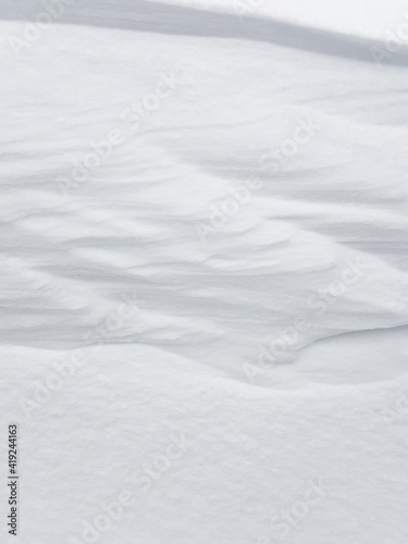 Pure white snow background texture. Winter background with snow embankments. Snow drifts after a blizzard, present. Details of the seasonal landscape. Cold weather. © iuliiawhite