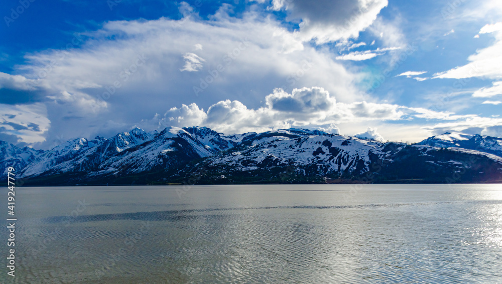View of the snow-capped mountains in the clouds near the lake Gren Titon, US