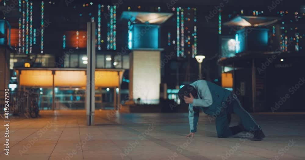Cool hip young dancer impressive breakdancing moves in city street at night