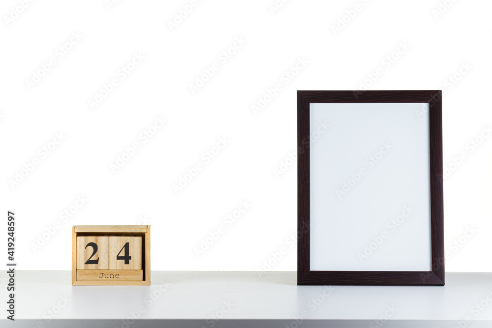 Wooden calendar 24 June with frame for photo on white table and background Wooden calendar 24 June with frame for photo on white table and background