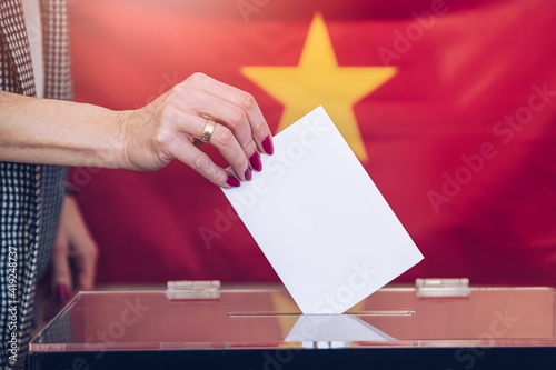 Woman holds envelope in hand above vote ballot. Election in Vietnam. photo