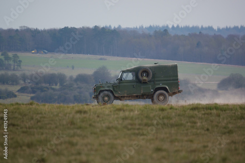 Fototapet british army land rover defender kicking up dust along a track