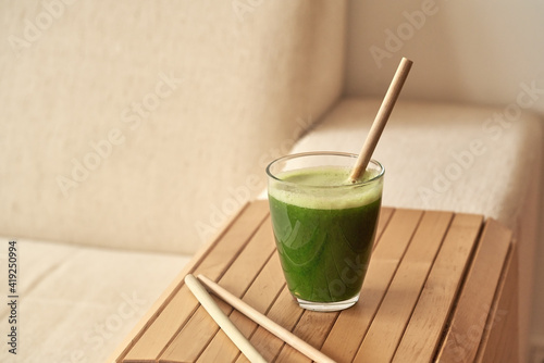 A glass of green juice with a bamboo straw - zero waste concept photo
