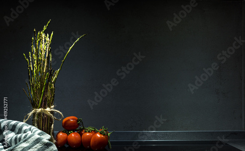 Bunch of wild asparagus with tomatoes. Black background