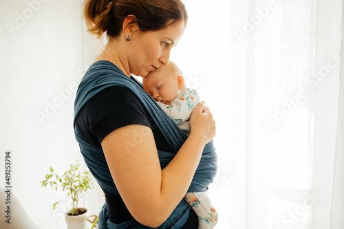 Attachment parenting concept. Young mother with baby in sling photo