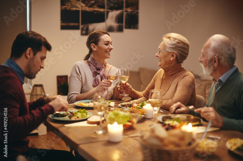 Happy women toasting with wine during family dinner at dining table.