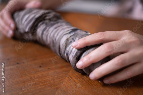 Eco print process: Female hands unrolling a bundle of fabric or printed cloth. Ecological and natural dyeing © David