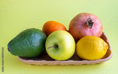 A small collection of fresh fruits in eco-friendly packaging on a yellow background