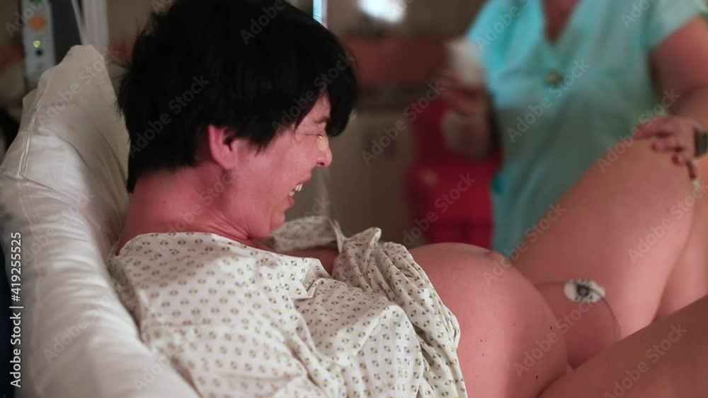 Mother's day concept. A woman in labor, with painful contractions, lying in delivery room bed. Childbirth and baby delivery. Natural childbirth and pain during labor.  Mom and newborn baby.