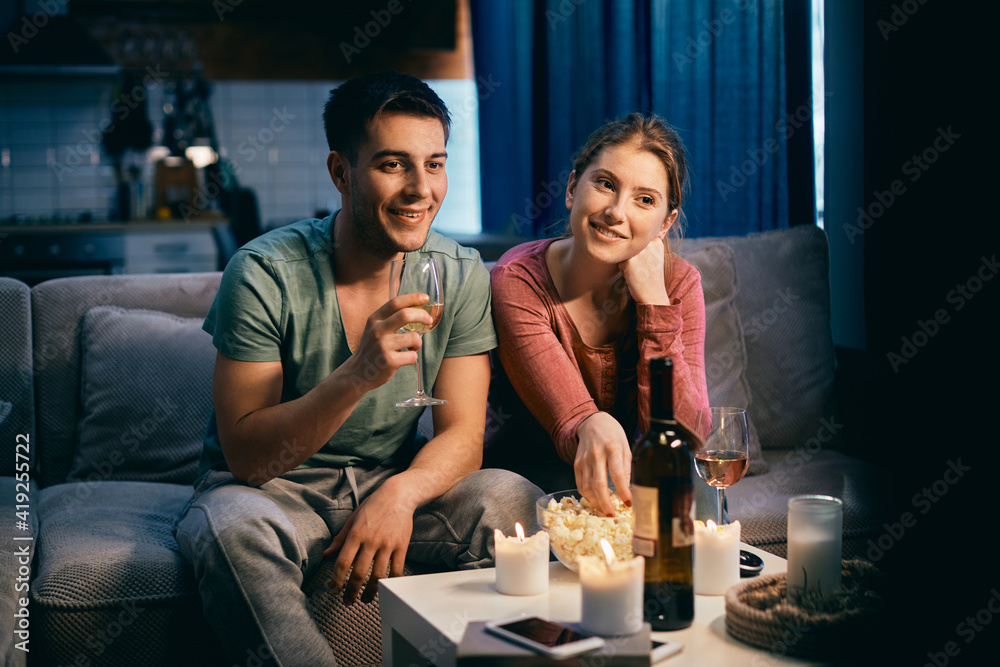 Young happy couple enjoying in movie night at home.