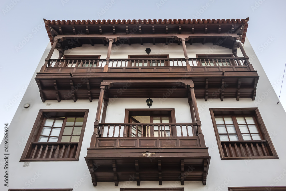 Facade of old building with a wooden balcony on a street in Spanish town Puerto de la Cruz on a sunny day. Puerto de la Cruz town, Tenerife, Canary Islands, Spain. Facade of old building with a wooden balcony on a street in Spanish town Puerto de la Cruz on a sunny day. Puerto de la Cruz town, Tenerife, Canary Islands, Spain.