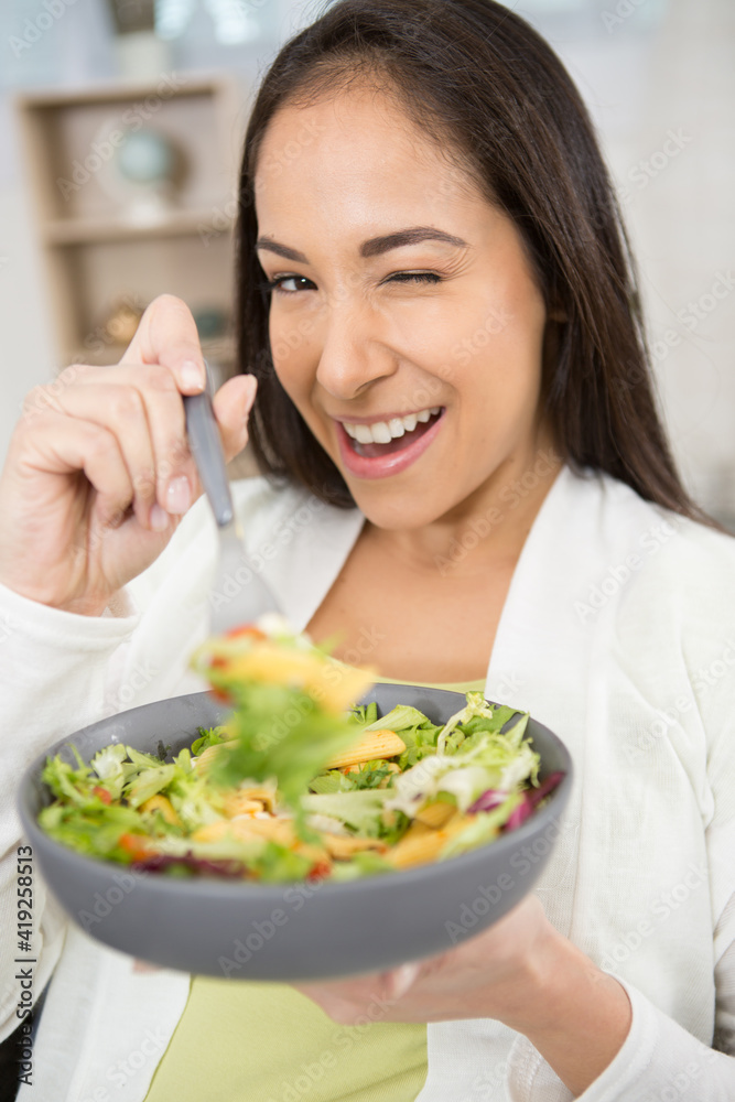 woman eating vegetable salad at table in kitchen woman eating vegetable salad at table in kitchen
