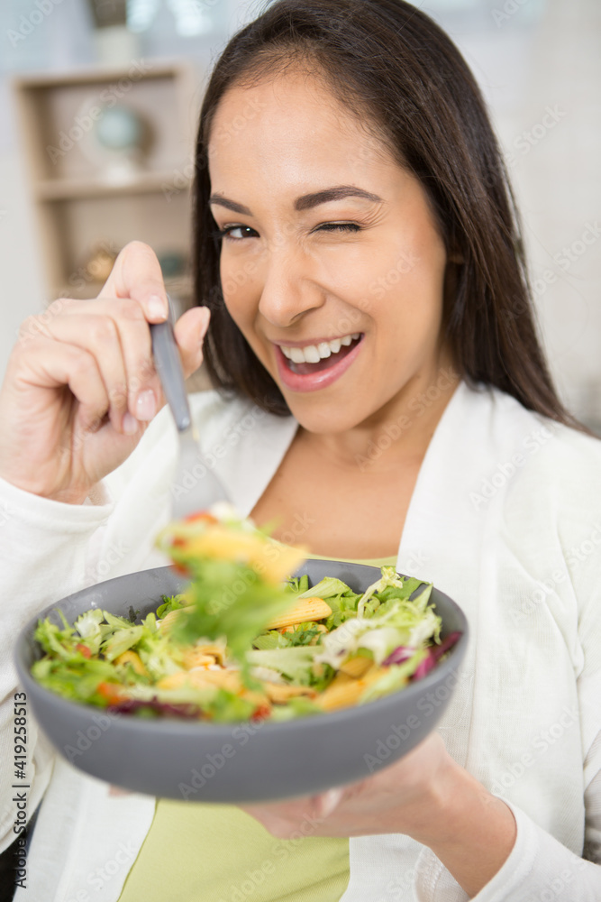 woman eating vegetable salad at table in kitchen