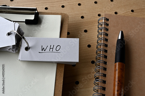 There's a notebook, and a clipboard with a wordbook on it that says WHO. photo