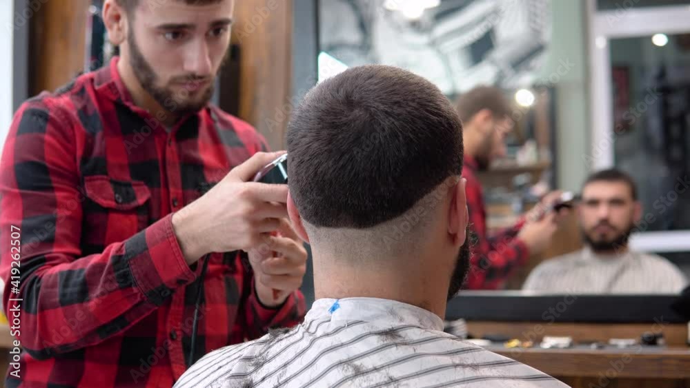 Young hairdresser and client during a haircut in a shoe beauty salon. Mirror view Young hairdresser and client during a haircut in a shoe beauty salon. Mirror view