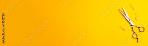 Banner template flat lay of professional hair cutting shears and bannies on yellow background Hairdresser salon equipment concept with copy space Selfcare on Easter holidays lockdown time