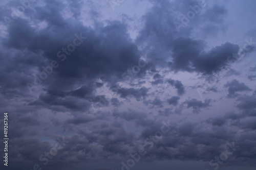 Dark blue violet twilight night storm sky with many fluffy clouds
