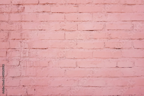 The texture of the building facade of a brick wall from rows of bricks painted in pink color