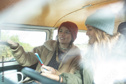 Young women friends using smart phone inside camper van photo