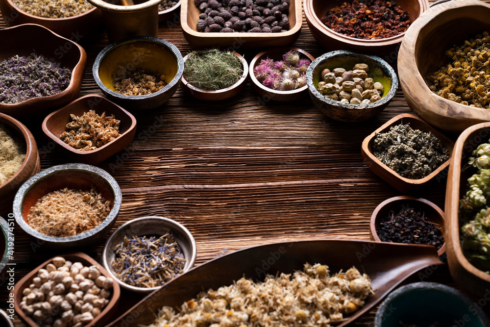 Natural medicine background. Assorted dry herbs in bowls and brass mortar on rustic wooden table. Natural medicine background. Assorted dry herbs in bowls and brass mortar on rustic wooden table.