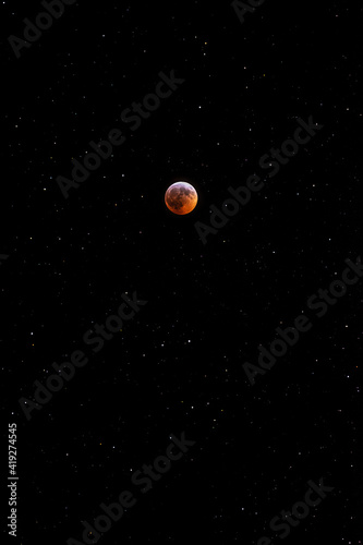 The Blood Moon Lunar Eclipse in front of a starry night sky.