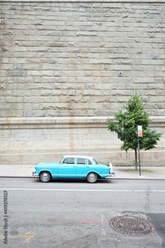 Turquoise Blue Car parked on street next to tree