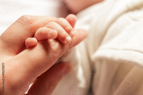 Mother holding the hand of her newborn baby photo