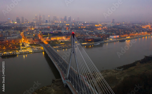 Illuminated cityscape of Warsaw with Vistula river and Swietokrzyski Bridge at dusk, Poland