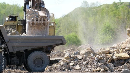 Video of excavator loads stones onto a dump truck on a open pit photo