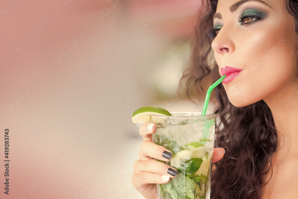 Young woman drinking mojito cocktail from mint soda light rum and lime with straw. Young woman drinking mojito cocktail from mint soda light rum and lime with straw.