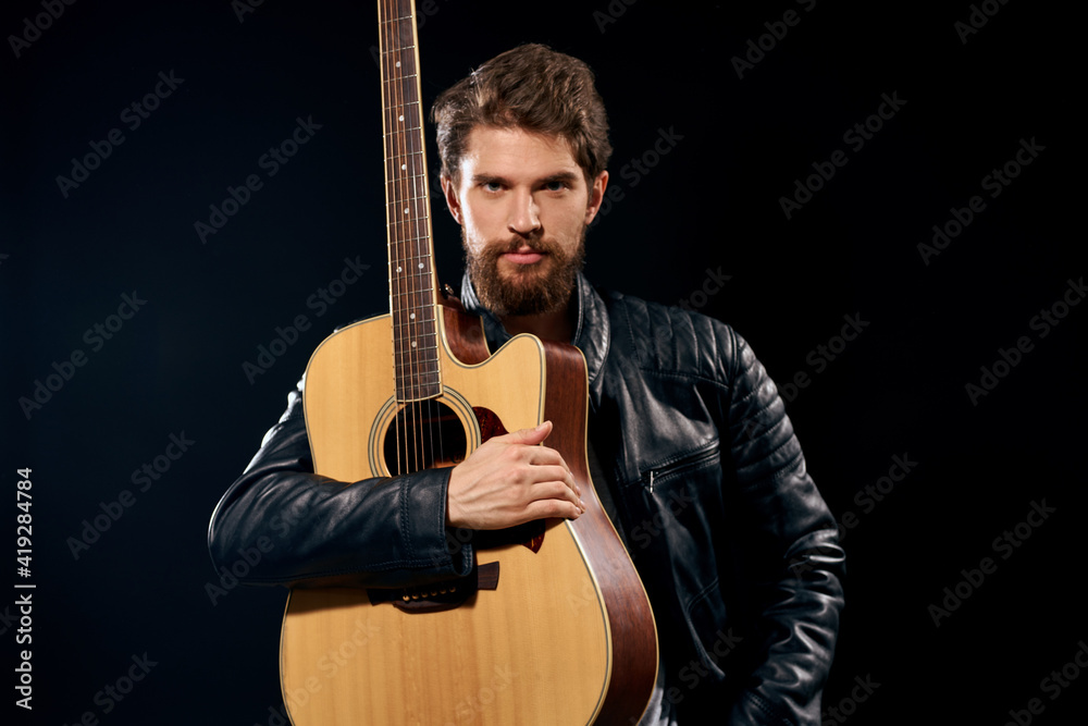 Obraz premium A man with a guitar in his hands leather jacket music performance rock star modern style dark background