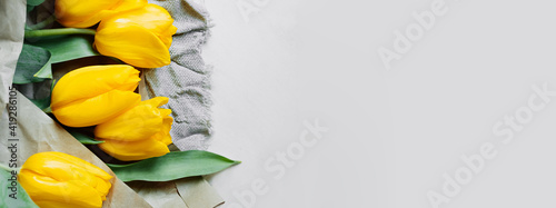 long format banner eco reusable craft paper and fabric packaging and bouquet of fresh yellow tulips. reasonable consumption, reasonable packaging and storage. selective focus photo