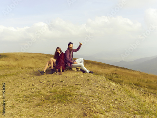 Couple hipsters sitting on stone on mountain top on natural background.