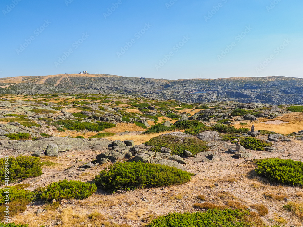 Fototapeta premium Wild Portuguese landscape. Mountain peak of Serra da Estrela or Star Mountain Range visible in the distance, with abandoned observatory. Highest place of Portugal during summer. Beautiful scenery.