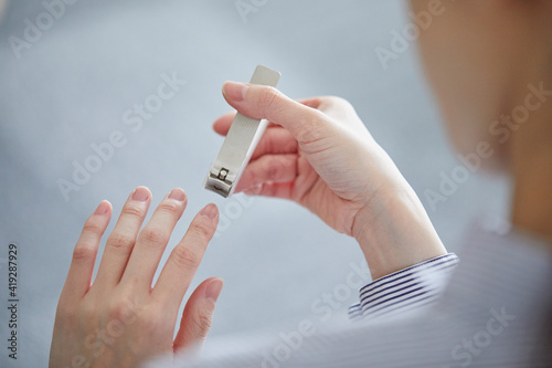 爪切りで爪を切る女性の手元 photo