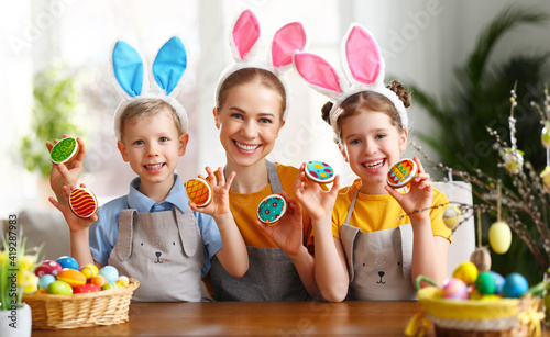 Positive mother and kids with Easter cookies at home