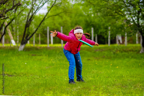 girl throws a disc on a green lawn