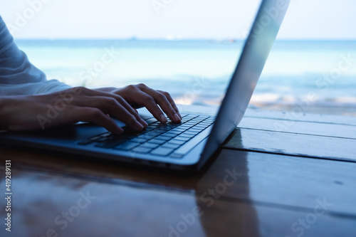 Closeup of a woman working and typing on laptop computer on the beach