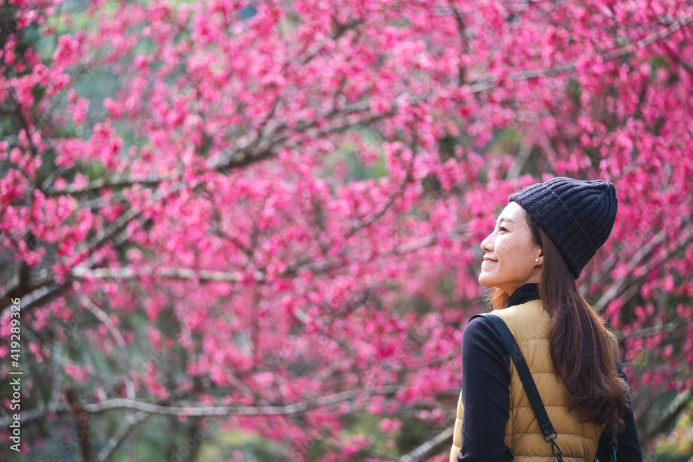 Portrait image of a beautiful young asian woman with pink cherry blossom flower in background Portrait image of a beautiful young asian woman with pink cherry blossom flower in background