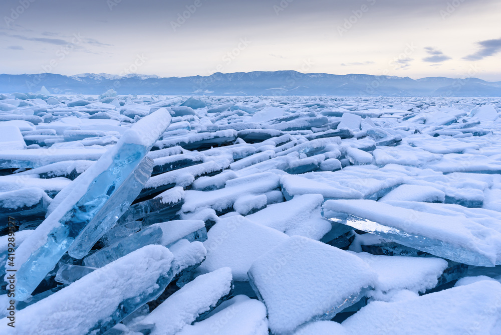 Obraz premium Endless hummock field on the frozen Lake Baikal. Piles of snow-covered debris of blue ice on a frosty day. Cold natural background. Unusual winter landscape
