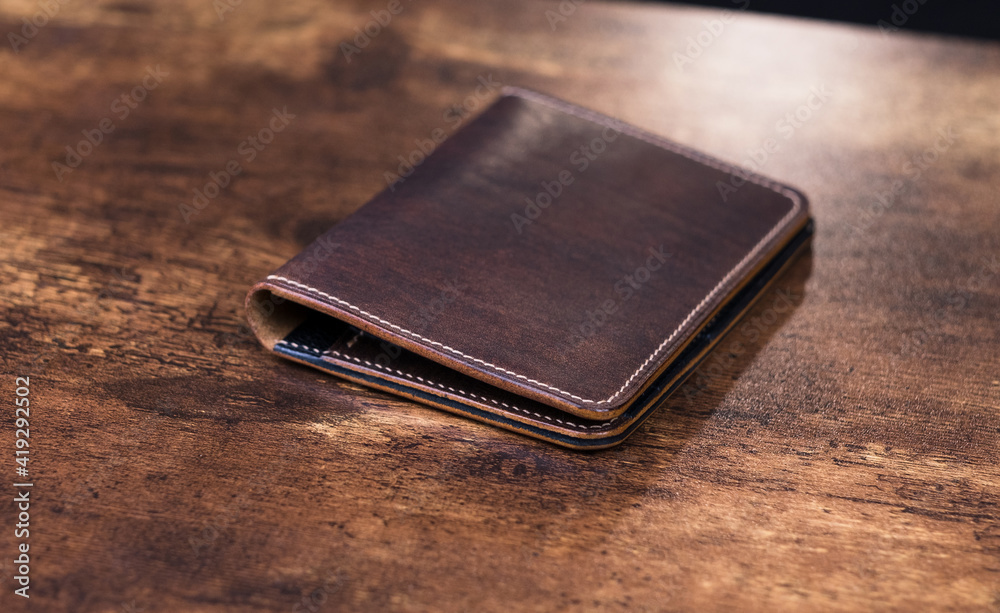 Stylish handmade leather men's wallet on wooden background. Genuine leather craft. Stylish handmade leather men's wallet on wooden background. Genuine leather craft.