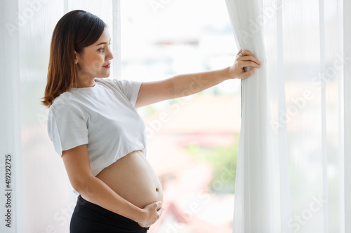 Asian woman pregnant mother standing by the window in white bedroom Free Download Asian woman pregnant mother standing by the window in white bedroom - GFXLoad