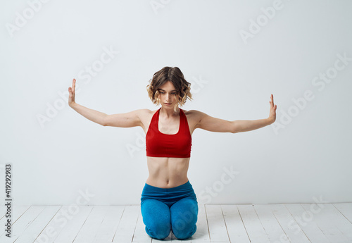 Woman in sportswear on a light background gestures with her hands yoga asana