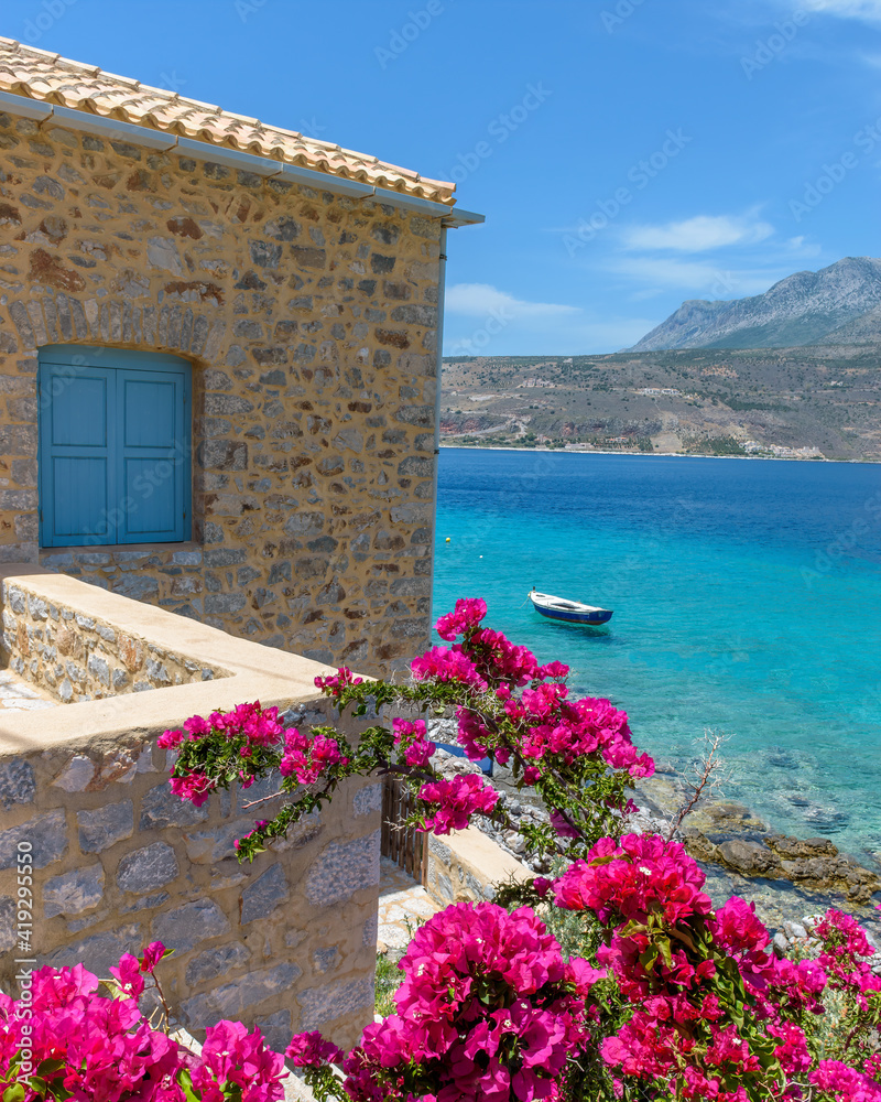 Limeni village with the famous  stone buildings a blooming bougainvillea, and turquoise waters in Mani, South Peloponnese , Greece.