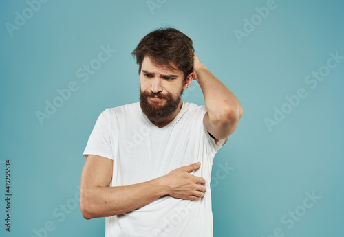 A brunette guy with a thick beard on a blue background gestures with his hands cropped view