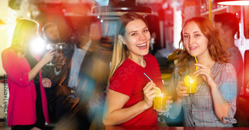 Portrait of smiling young women drinking cocktails and talking on party