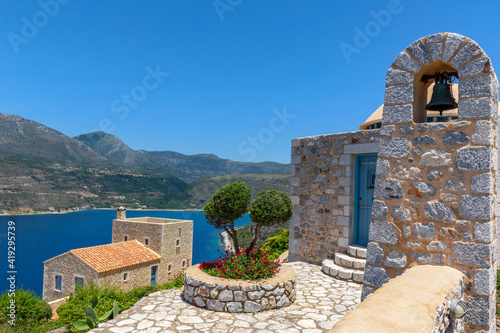 view of a traditional stone build towerbell and an exterior of a church  with panoramic view of the gulf of oitilo as a background  near Areopoli, peloponnese , Greece.. photo