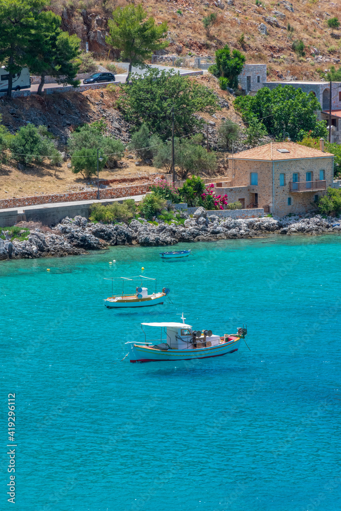 Fototapeta premium view of Limeni village with fishing boats in turquoise waters and the stone buildings as a background in Mani, South Peloponnese , Greece.