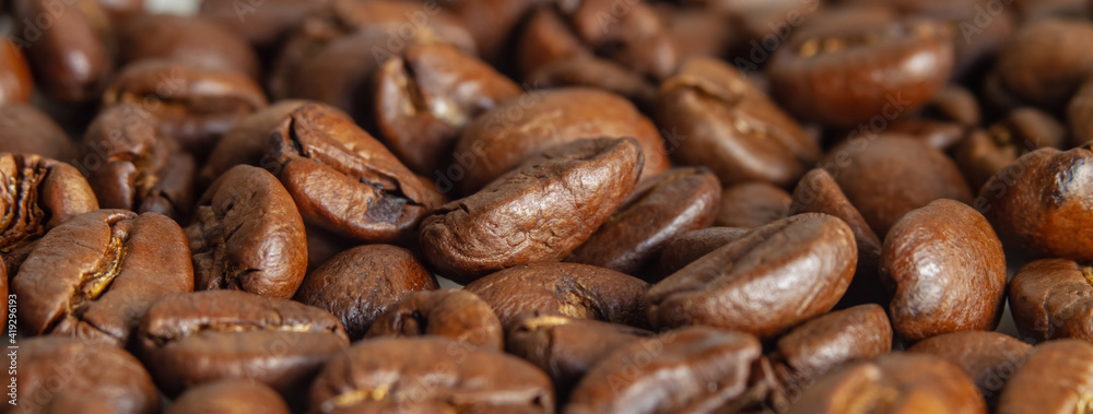 Fototapeta premium Freshly roasted coffee beans in a macro photo. Side view